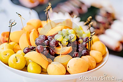 assorted fruit on a white plate. apricots, grapes, peaches and cherry plums Stock Photo