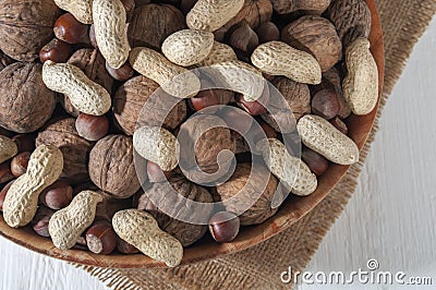 Assorted groundnuts, walnuts and hazelnuts. Nuts in a bowl on burlap. White wooden background. Close-up Stock Photo