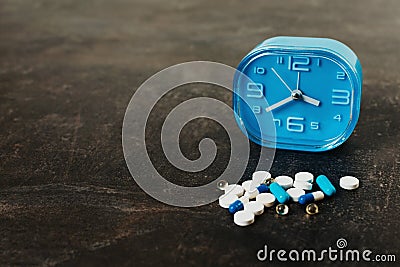 Assorted Pills and blue clock on dark table. healthy drug medicine concept Stock Photo