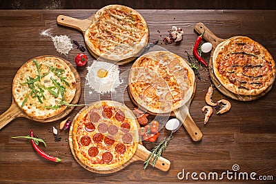 Assorted pizza with seafood and cheese, four cheeses, pepperoni, meat, margarita on a wooden stand with spices Stock Photo