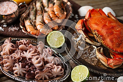 Assorted of seafood on rustic wooden table. Top view of tiger shrimps, cooked crab and baby octopuses served with lime and Stock Photo