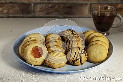 Assorted tea pastes on a blue plate and tea cup on brick background Stock Photo