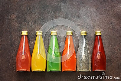 Assorted various colored drinks in bottles on a dark rustic background, border. Top view, flat lay Stock Photo