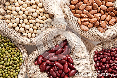 Assortment of beans and lentils in hemp sack on wooden background. green bean, groundnut, soybean, red kidney bean , black bean , Stock Photo