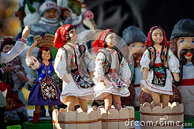 Assortment of clay Souvenirs in traditional moldovan suits. Souvenir clay figurines of women trample grapes in wooden skating Editorial Stock Photo