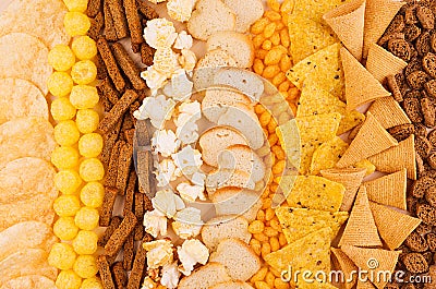 Assortment crunchy snacks - popcorn, nachos, croutons, corn sticks, potato chips as decorative background, top view, closeup. Stock Photo