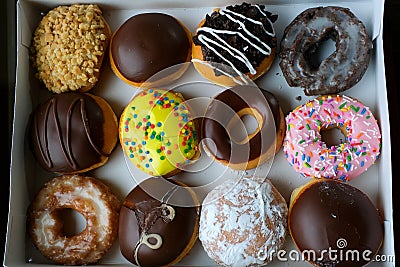Assortment of donuts of different flavors in a box. Close-up of tasty doughnuts with sprinkles on table Stock Photo