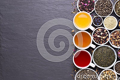 Assortment of dried tea leaves, fruit and herbs in bowls on dark, stone background Stock Photo