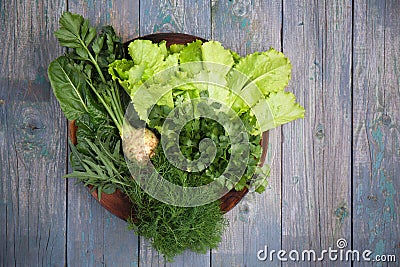 Assortment of fresh aromatic herbs on a wooden plate Stock Photo