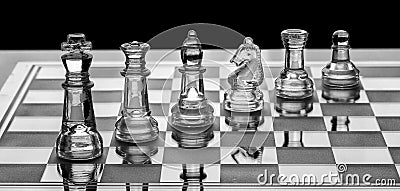 Assortment of glass chess pieces on a board with black and white Stock Photo