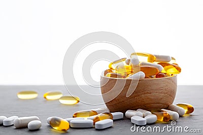 Assortment scattered pharmaceutical medicine tablets, pills, drugs in wooden bowl on gray background. White food dietary Stock Photo