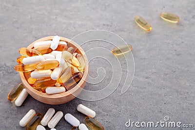 Assortment scattered pharmaceutical medicine tablets, pills, drugs in wooden bowl on gray background. White food dietary Stock Photo