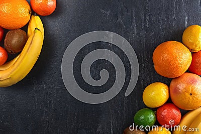 Assortment of tropical fruits orange, tangerine, banana, grapefruit, lemon, lime, kiwi on dark background. copy space Stock Photo