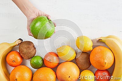 Assortment of tropical fruits orange, tangerine, banana, grapefruit, lemon, lime, kiwi. Fresh fruit with apple on hand Stock Photo