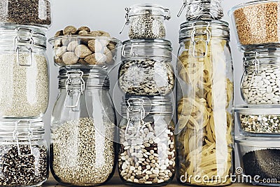 Assortment of uncooked grains, cereals and pasta in glass jars on wooden table. Healthy cooking, clean eating, zero Stock Photo