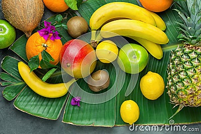 Assortment Variety of Tropical Seasonal Summer Fruits Pineapple Mango Oranges Lemons Kiwi Coconut Bananas on Large Palm Leaf Stock Photo