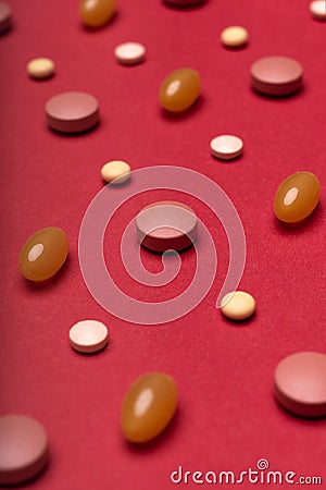 Assortment of various colourful pills red coloured background. Medication and prescription pills. Stock Photo