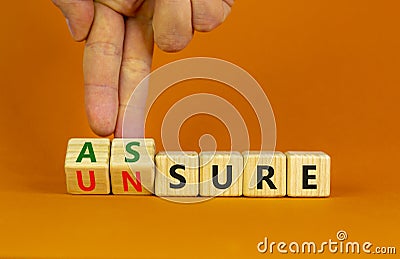 Assure or unsure symbol. Businessman turns wooden cubes and changes the concept word unsure to assure. Beautiful orange table, Stock Photo