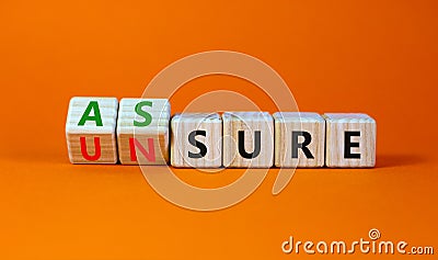 Assure or unsure symbol. Turned wooden cubes and changed the concept word unsure to assure. Beautiful orange table, orange Stock Photo