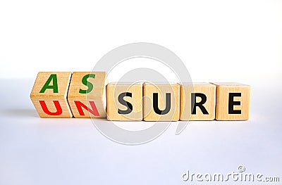 Assure or unsure symbol. Turned wooden cubes and changed the concept word unsure to assure. Beautiful white table, white Stock Photo