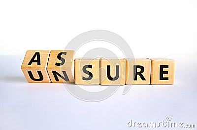 Assure or unsure symbol. Turned wooden cubes and changed the concept word unsure to assure. Beautiful white table, white Stock Photo