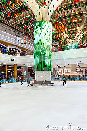 Happy children and adults go ice skating on an indoor ice rink in a modern shopping mall. Editorial Stock Photo