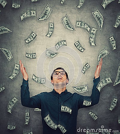 Astonished businessman raising up hands as money are falling like dollars rain. Surprised guy open mouth stunned expression, Stock Photo