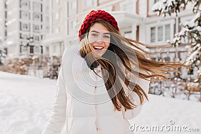 Astonished happy girl in red hat having fun in frozen morning on street full with snow. Expressing positivity, true Stock Photo