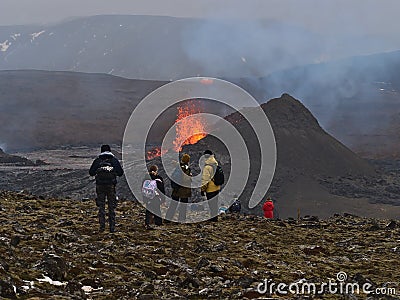 Astonished people watching lava explosion of volcanic eruption at Fagradalsfjall with women pointing on the volcano with smoke. Editorial Stock Photo