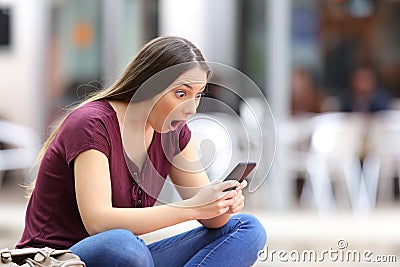 Astonished woman with a phone in the street Stock Photo