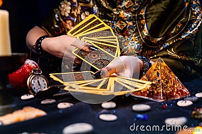 Astrology and esotericism. A fortune teller holds a fan of Tarot cards. On the table are runes and talismans. Close-up of hands Stock Photo