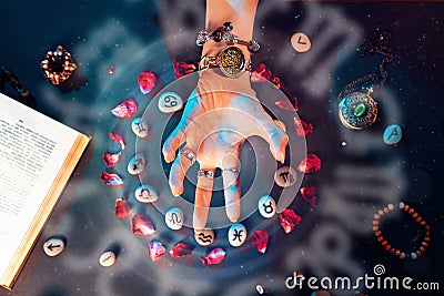 Astrology and horoscope. A woman's hand conjures stones with the signs of the zodiac, laid out in a circle and decorated Stock Photo