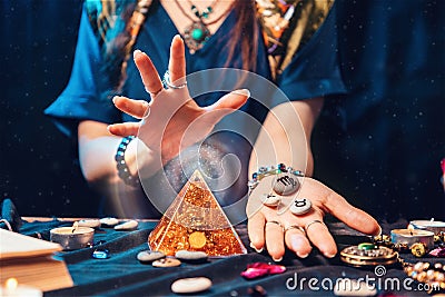 Astrology and magic. A fortune teller holds stones with the sign of the zodiac in her hands and conjures a magic pyramid Stock Photo