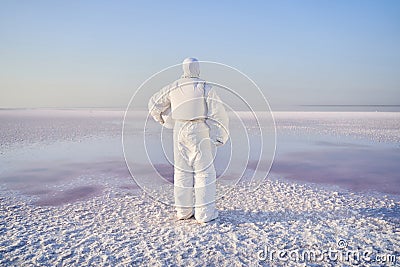 Astronaut standing with back on salty lake Stock Photo