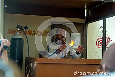 Egyptian artisan worker located at the door of a perfume factory in Aswan molding glass Editorial Stock Photo