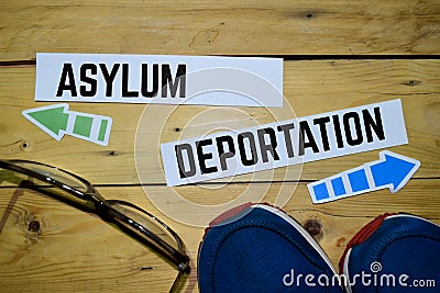Asylum or Deportation opposite direction signs with sneakers and eyeglasses on wooden Stock Photo
