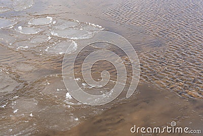 ater swirls and forms a texture through which you can see yellow sand Stock Photo