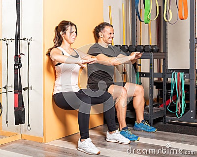 Athete people doing squats leaning on wall in gym Stock Photo