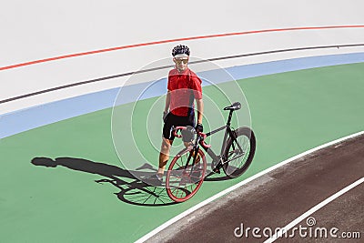 Athlete with a black bicycle at velodrome Stock Photo