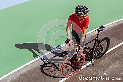 Athlete with a black bicycle at velodrome Stock Photo