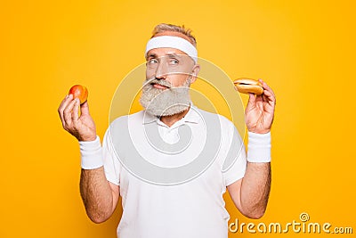 Athlete cool grandpa holds forbidden junkfood cheeseburger and f Stock Photo