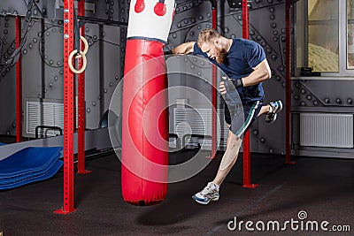 Athlete fighter of mixed martial arts in jump inflicts powerful blow with his hand on punching bag. Stock Photo