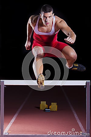 Athlete on hurdle in track and field Stock Photo