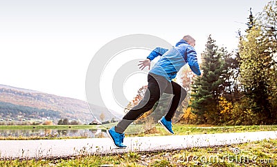 Athlete at the lake running against colorful autumn nature. Stock Photo