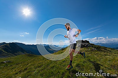 Athlete man practicing mountain running in the sun at high altitude Stock Photo