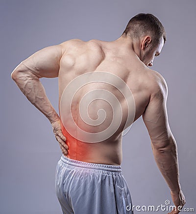 Athlete muscular man has pain in the back. Red Stock Photo