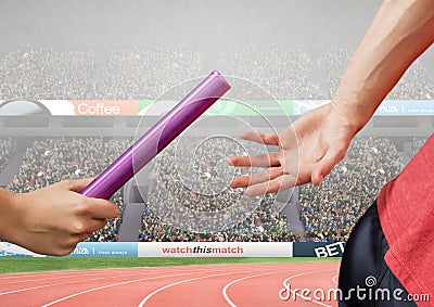 Athlete passing baton during relay race against stadium in background Stock Photo