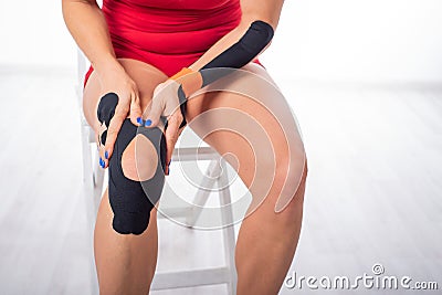 The athlete puts a medical tape on his knee. alternative treatment for joint and tendon injuries. Physiotherapy of Stock Photo