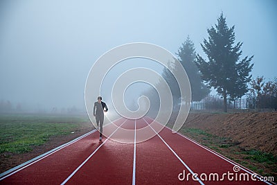 Athlete at the Running track with red lines over misty blue sky. Sport photo, edit space Stock Photo