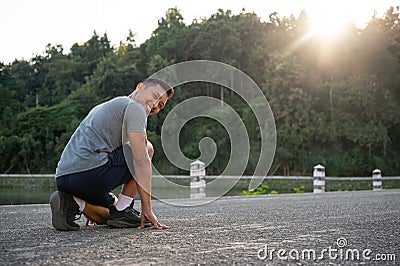 An athlete, strong Asian male runner is getting ready to run, exercising outdoors in the morning Stock Photo